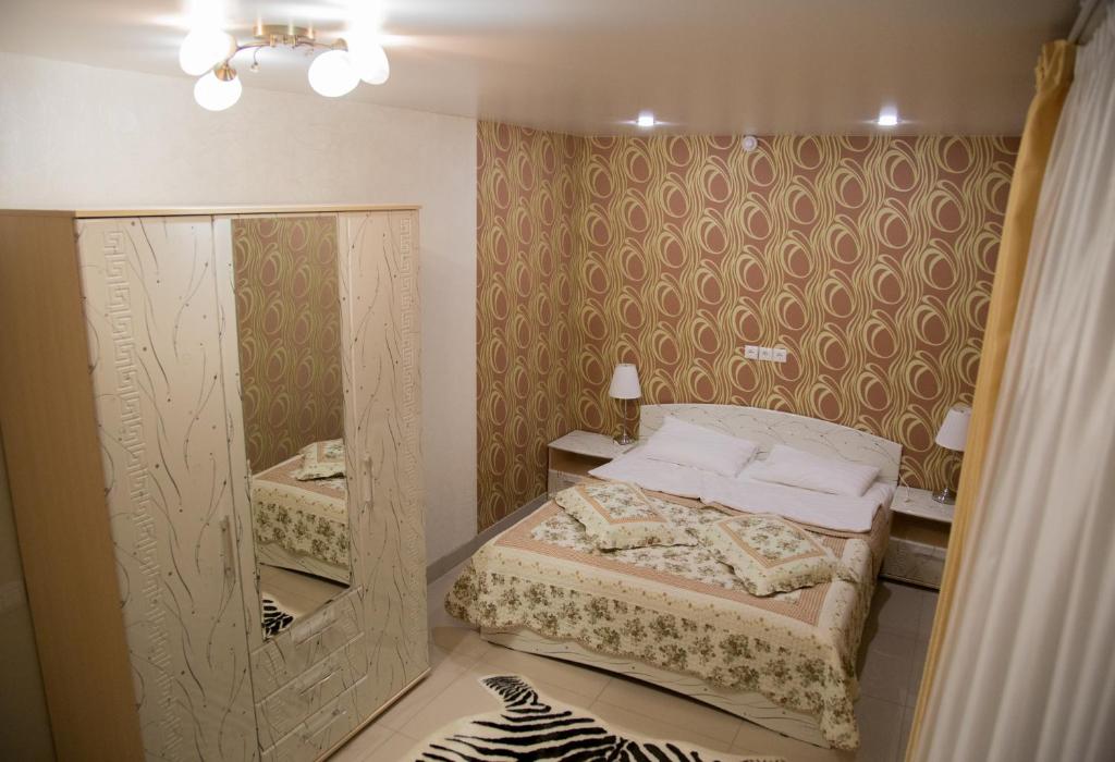 Dormitorio pequeño con cama y espejo en Orange Club, en Zarechnyy