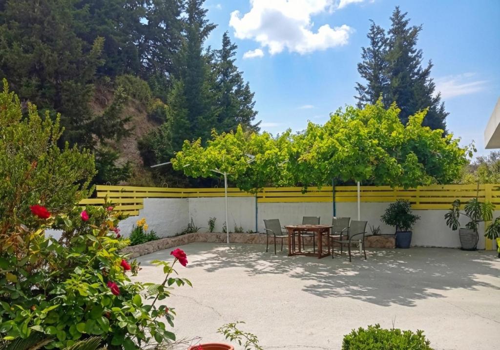 a patio with a table and chairs and trees at Seascape Village - Spacious 3-Bed Apartment with Private Garden and Parking in Kalithies