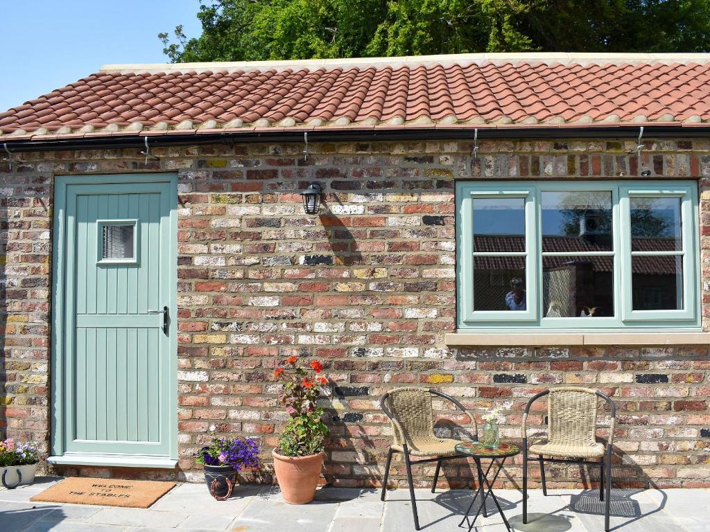a brick house with a green door and chairs at The Stables - Uk13196 in Butterwick