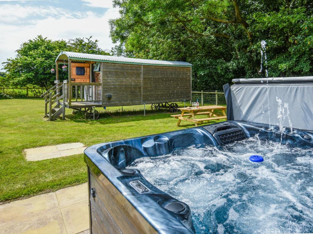 a hot tub in a yard with a play house at Bluebell - Shepherd Hut - Uk49948 in Oswestry