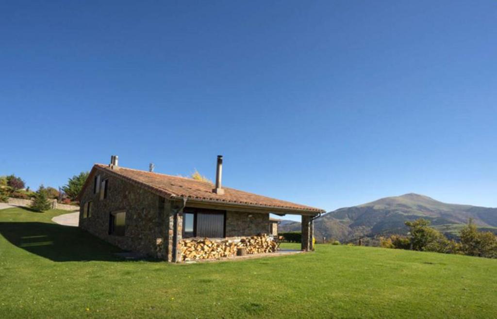 CasaCampelles I - Vall de Núria - Ripollès في Campelles: بيت حجري في حقل فيه جبال في الخلف