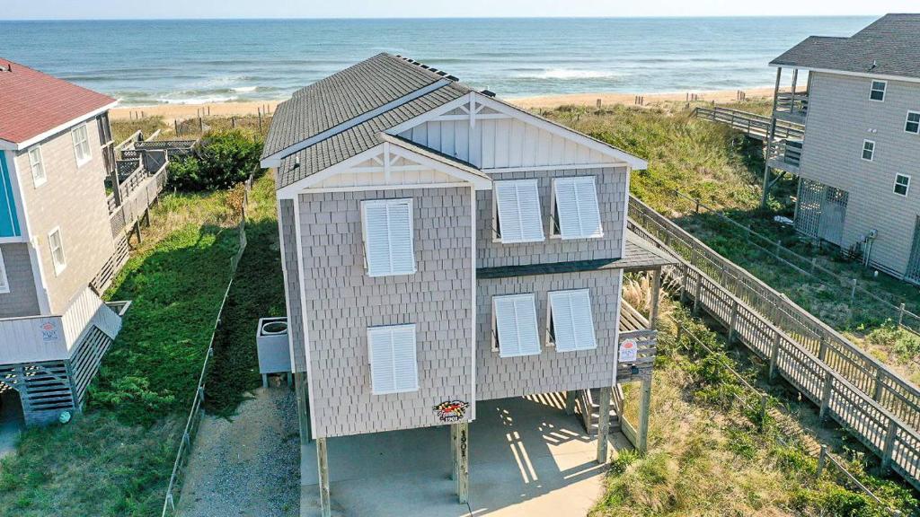 a house on the beach next to the ocean at T.L. Sea - KDH MP 6, Oceanfront, Ocean view, Rec Room, Spacious Decks, Private Walk to Beach in Kill Devil Hills