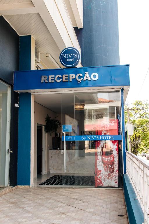 a store with a blue sign on the front of a building at Niv's Hotel in Monte Sião