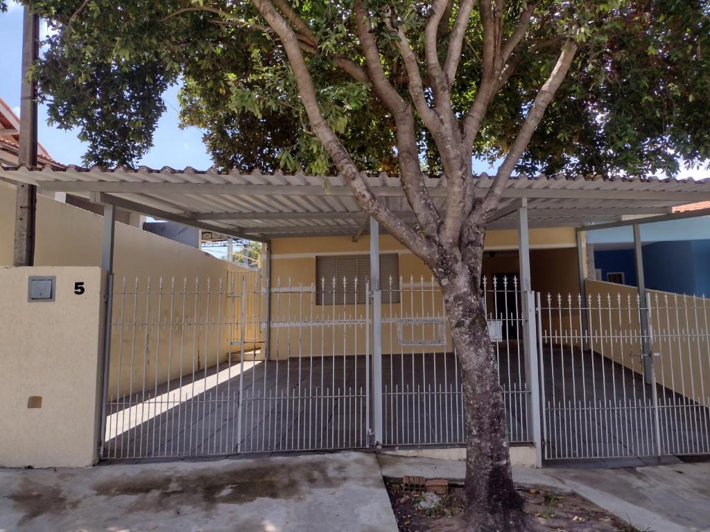 a fence with a tree in front of a building at Casa na área central com 3 quartos in São Pedro