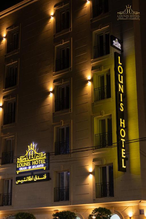 a hotel building with a hotel sign at night at Lounis Hôtel by Atlantis in Oran