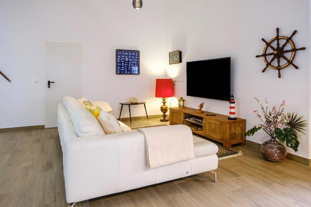 a living room with a white couch and a tv at Casa dos Andrades in Sesimbra
