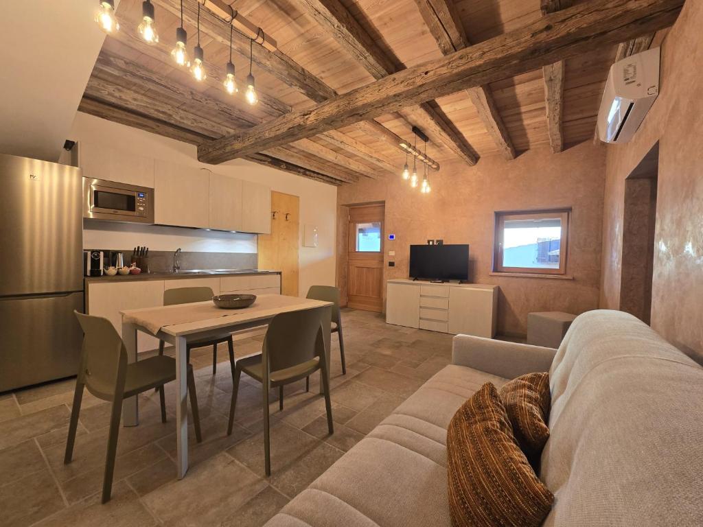 a living room with a couch and a table and a kitchen at Corte Cimiotti - Borgo Gortani in Sùtrio