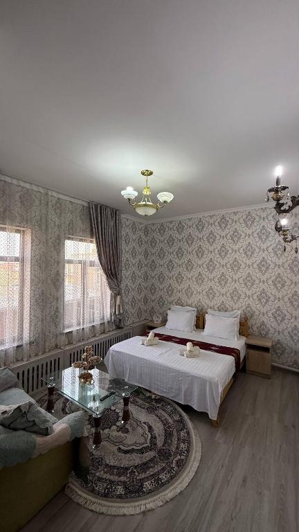 a bedroom with a bed and a couch and a table at Welcome to Villa Yaaxya in Bukhara