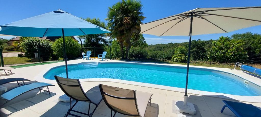 una piscina con dos sombrillas y sillas en La Grange, en Vézac