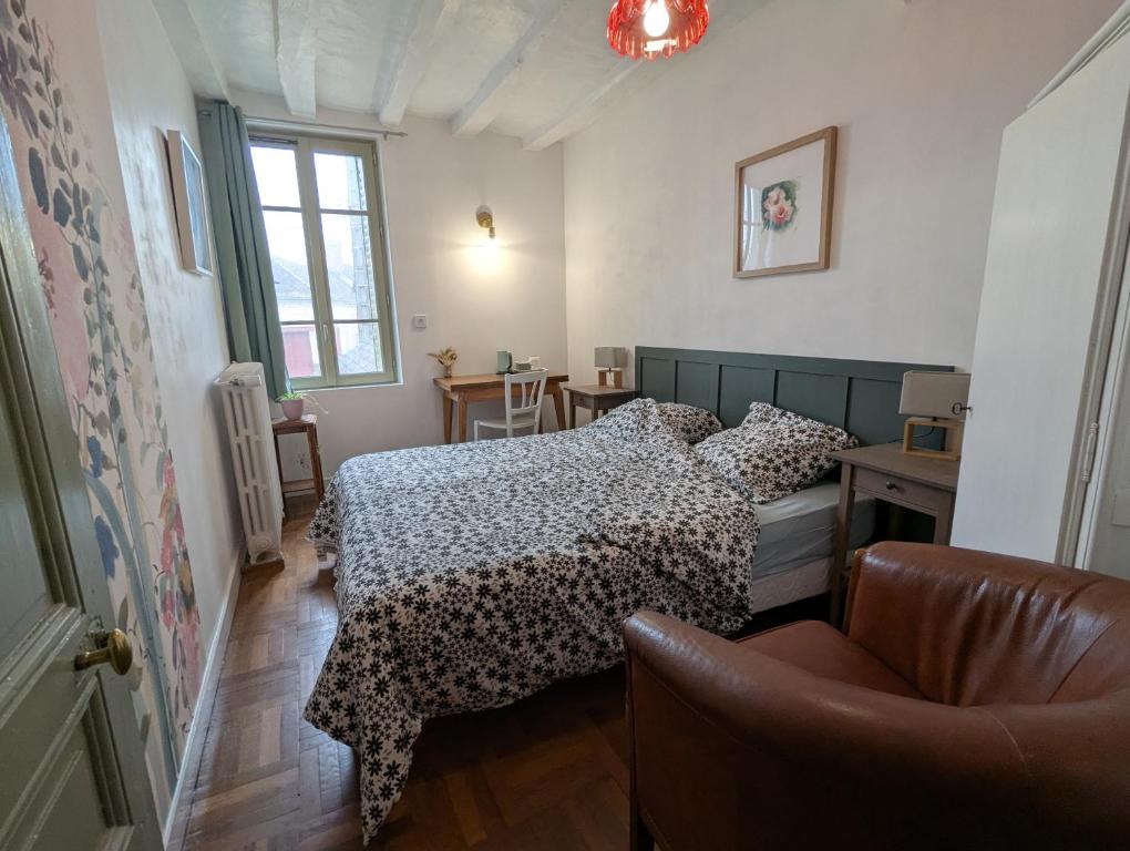 a bedroom with a bed and a chair at Le Tintamarre - Chambres et suite familiale à 5 min du Zoo de Beauval in Saint-Aignan