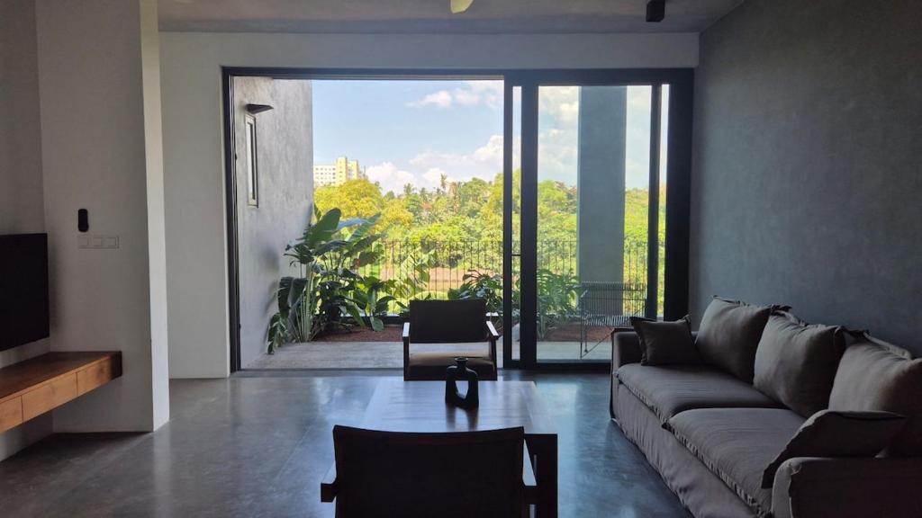 a living room with a couch and a large window at Stillwater Edge 2 - Level Two in Sri Jayewardenepura Kotte