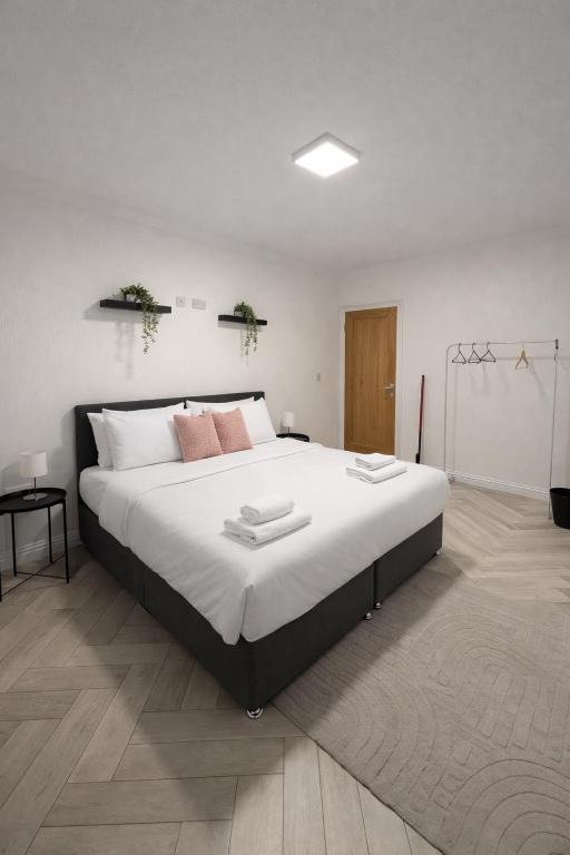 a bedroom with a large bed with white sheets and pink pillows at Modern Comfort for Longer Stays in Bury, 2-Bedrooms in Walmersley