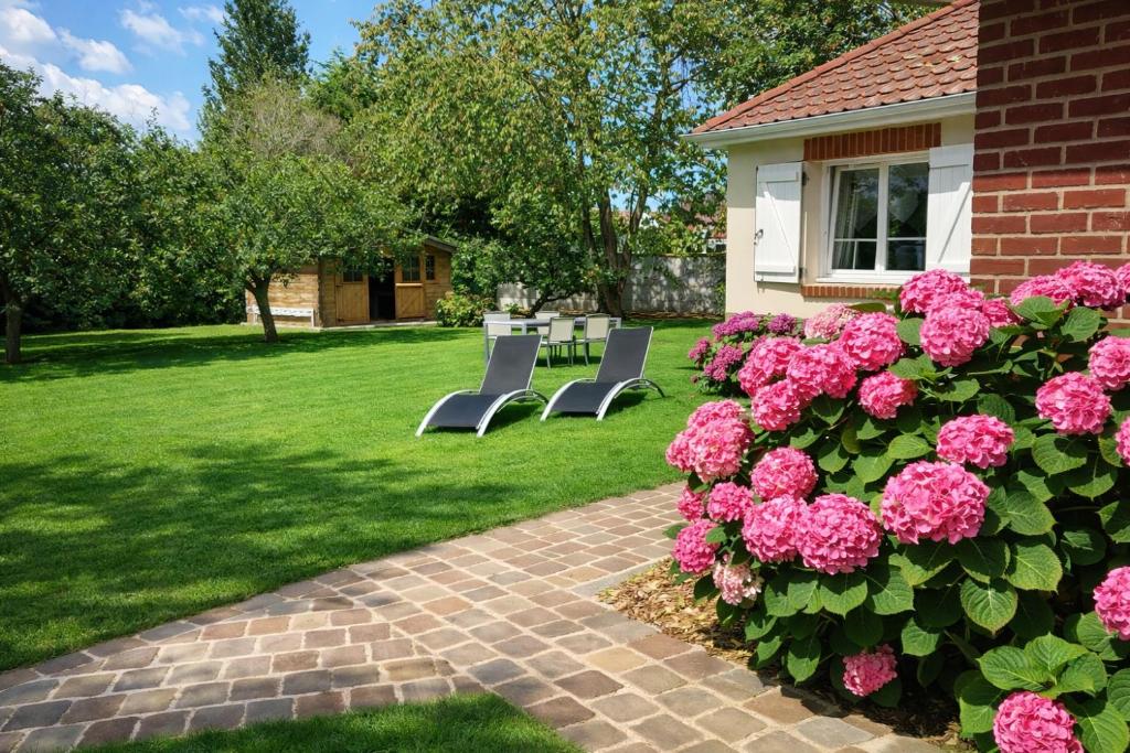 a garden with pink flowers and a table and chairs at Chambre d'Hotes Les Hortensias in Rang-du-Fliers