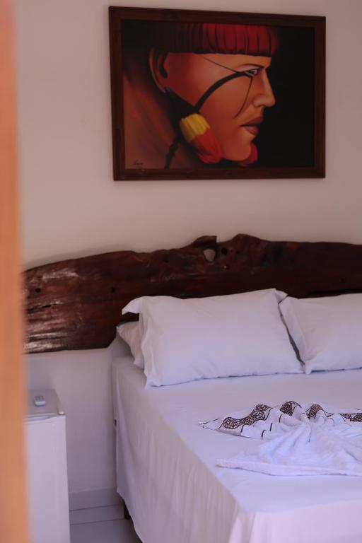 a bedroom with a bed with a painting on the wall at Pousada Santa Adélia - Boipeba BA in Ilha de Boipeba