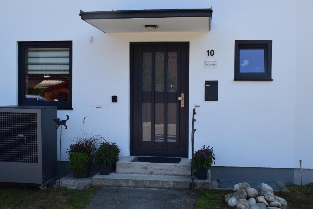 a white house with a black door and stairs at Ferienhaus LebensART in Bischofswiesen