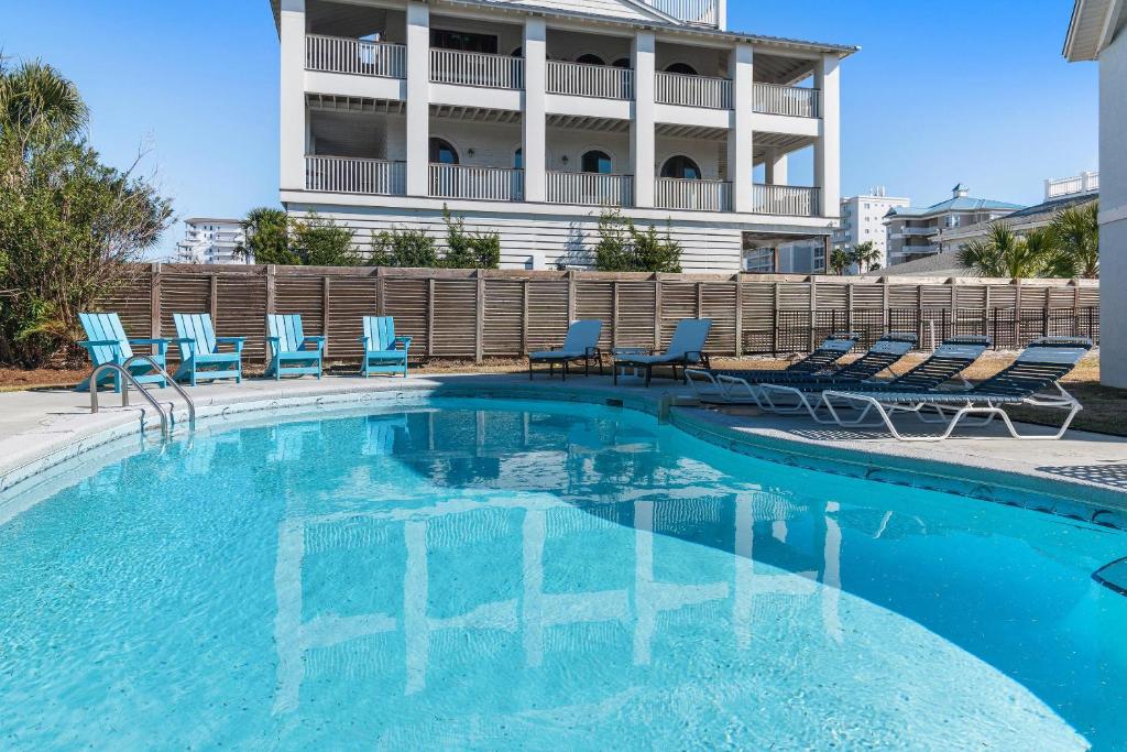 a swimming pool with blue chairs and a building at Sea-Esta in Destin