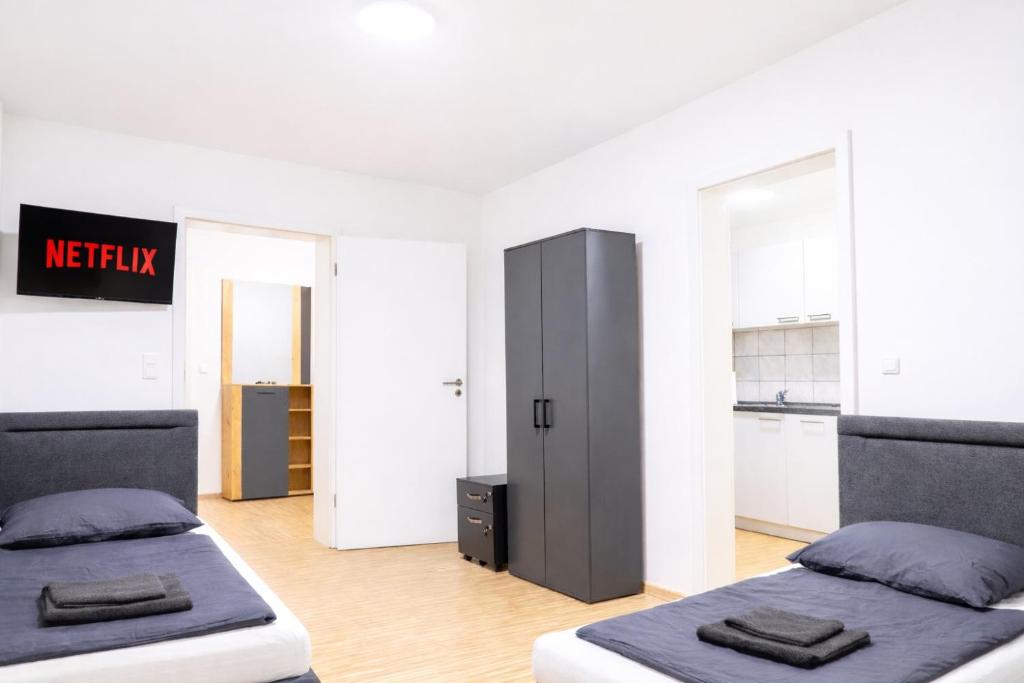 two beds in a room with a kitchen at LETA Homes - Komfortable FeWo mit Traumbalkon mit flexiblem, Self-Check-In & eigenen Parkplätzen in Straubing