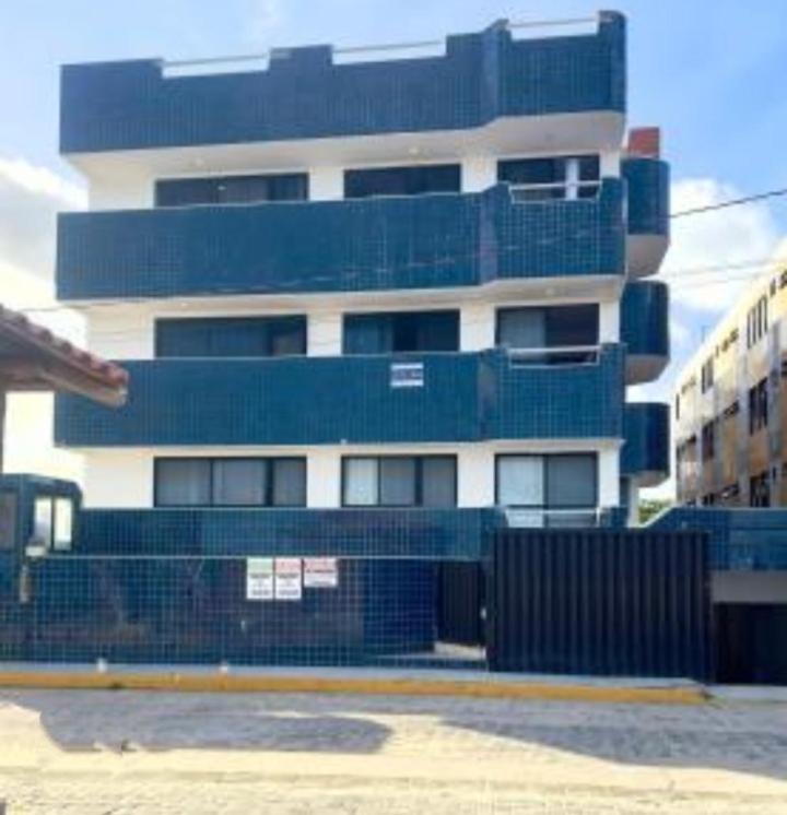 a tall building with a fence in front of it at Barrah flat in Barra de São Miguel