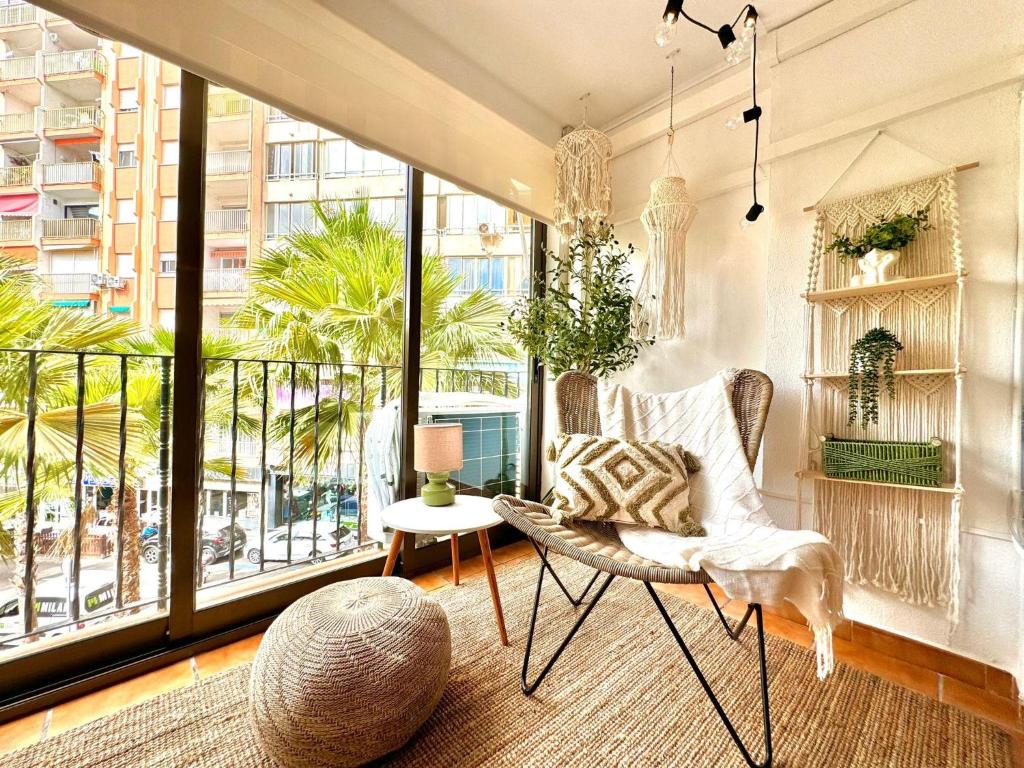 a room with a chair and a table and windows at La Palmera Suite Calpe in Calpe