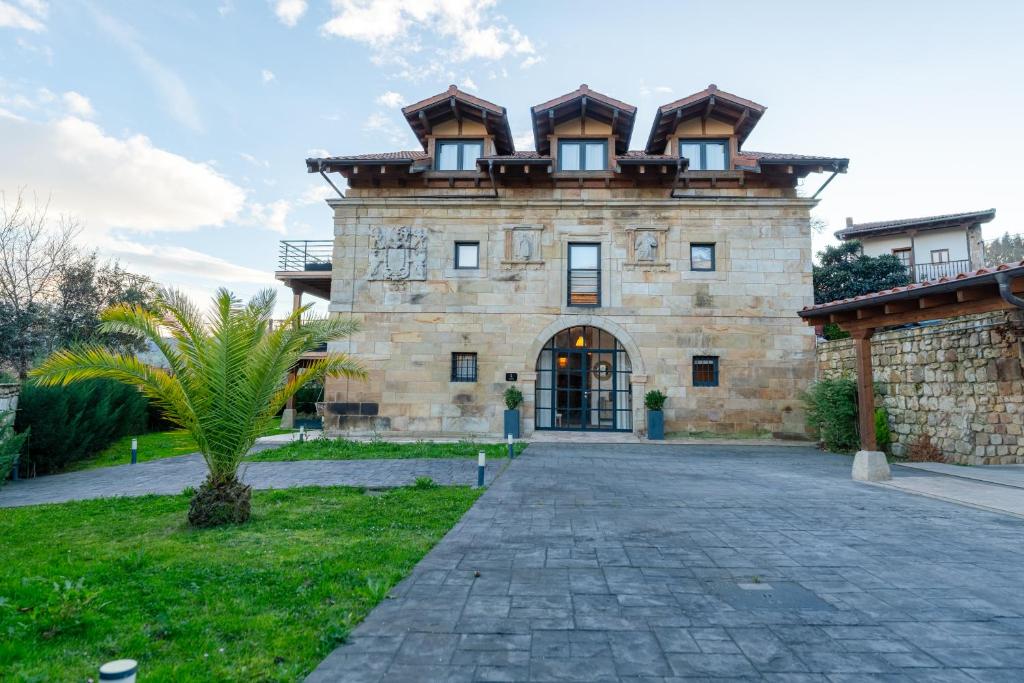 a large stone building with a roof at Sandoñana Old Palace Lodge in Villafufre