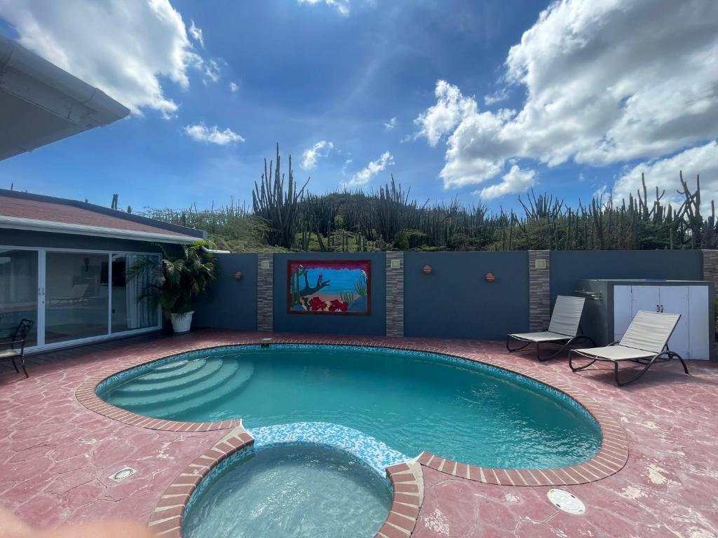 a swimming pool with two chairs and a tv in a yard at Cactus & Cove Villa in Santa Cruz