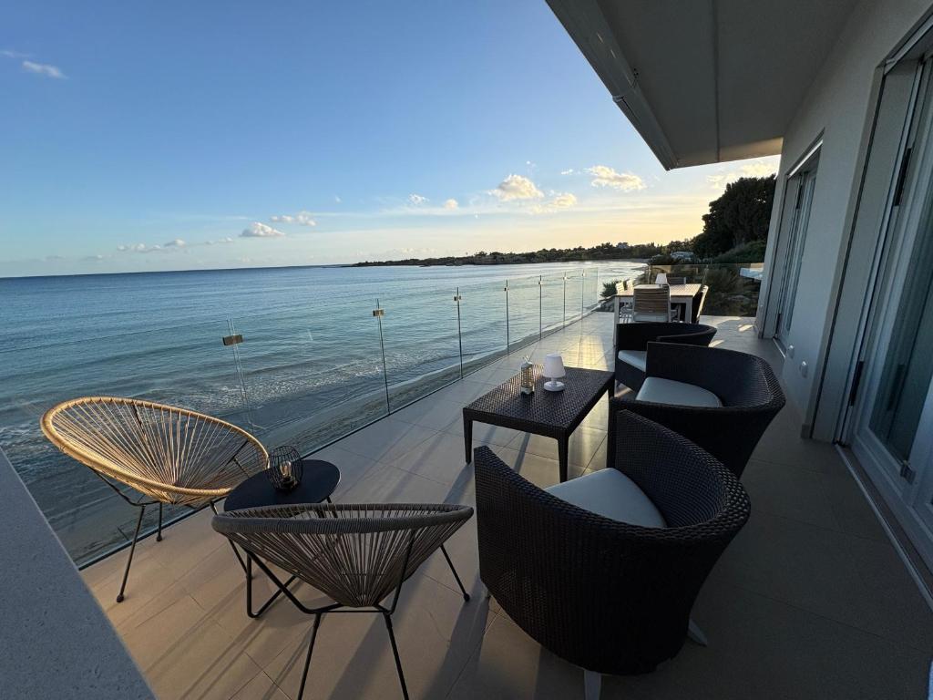 a balcony with chairs and tables and the ocean at Taormina 10 PANTA REI Fontane Bianche in Fontane Bianche