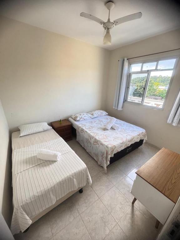 a bedroom with two beds and a window at Apê 250m da Orla de Piúma in Piúma