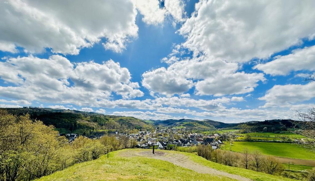 a view of a town from a hill with clouds at Komfort-Fewo mit Infrarotsauna & WLAN nahe Sorpesee - Haus am Krähenbach - Steinert in Sundern