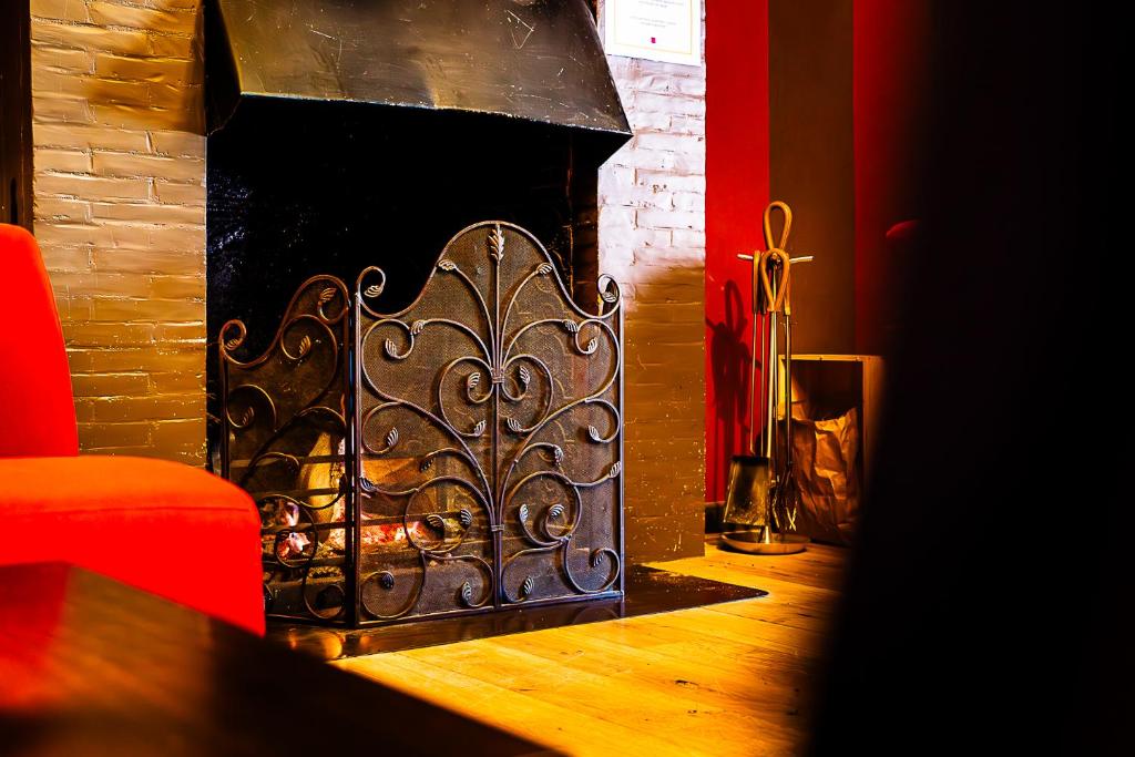a fireplace with a metal grate in a living room at Hotel Le Beau Séjour in Nassogne