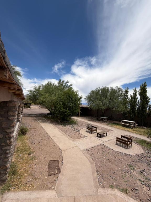 a walkway with benches and trees in a park at Posada Solar de las Piedras in Fiambalá