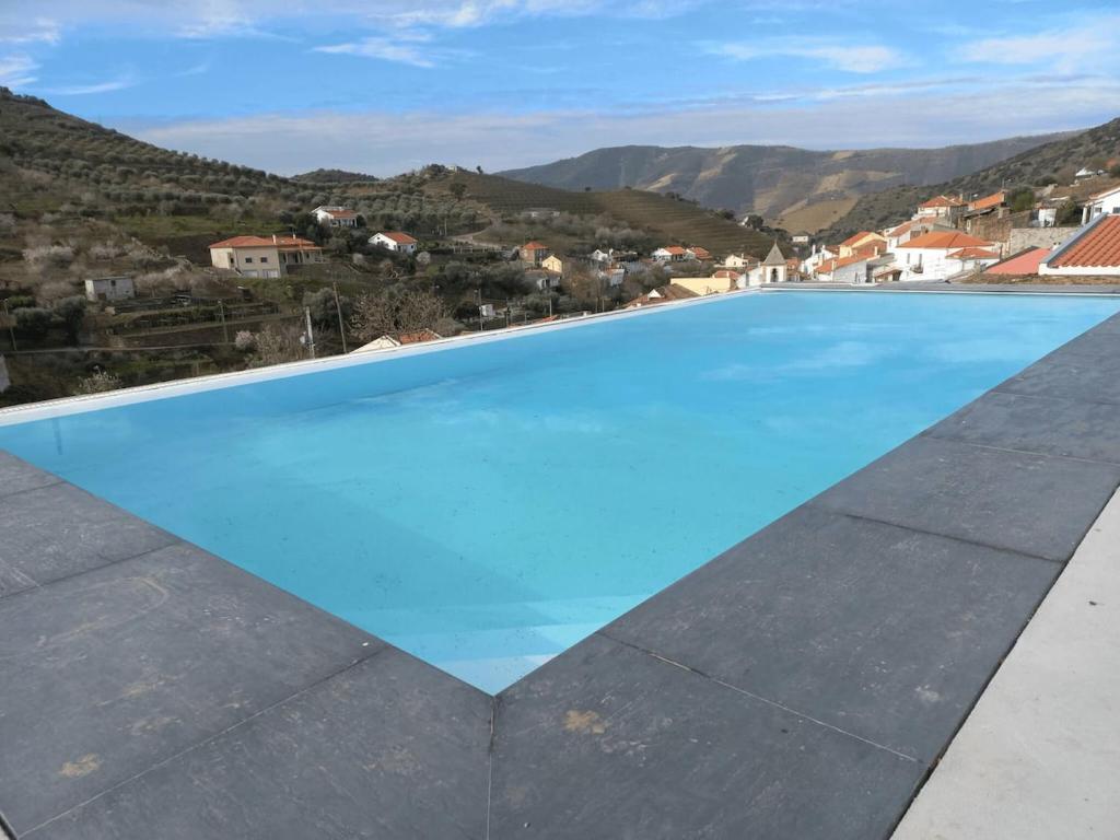 a large blue swimming pool with mountains in the background at EiraDouro - Casa Oliveira in Mós