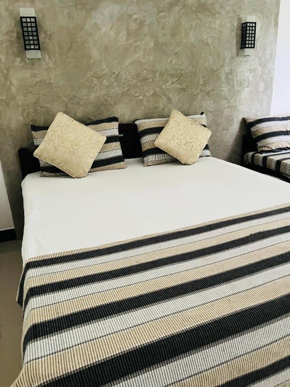 a bed with black and white striped sheets and pillows at Kingdom Gate Hotel in Anuradhapura
