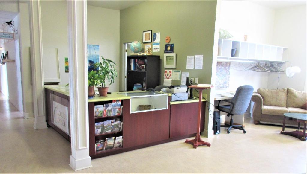a living room with a counter and a desk with a chair at Auberge La Petite École de Forillon in Gaspé