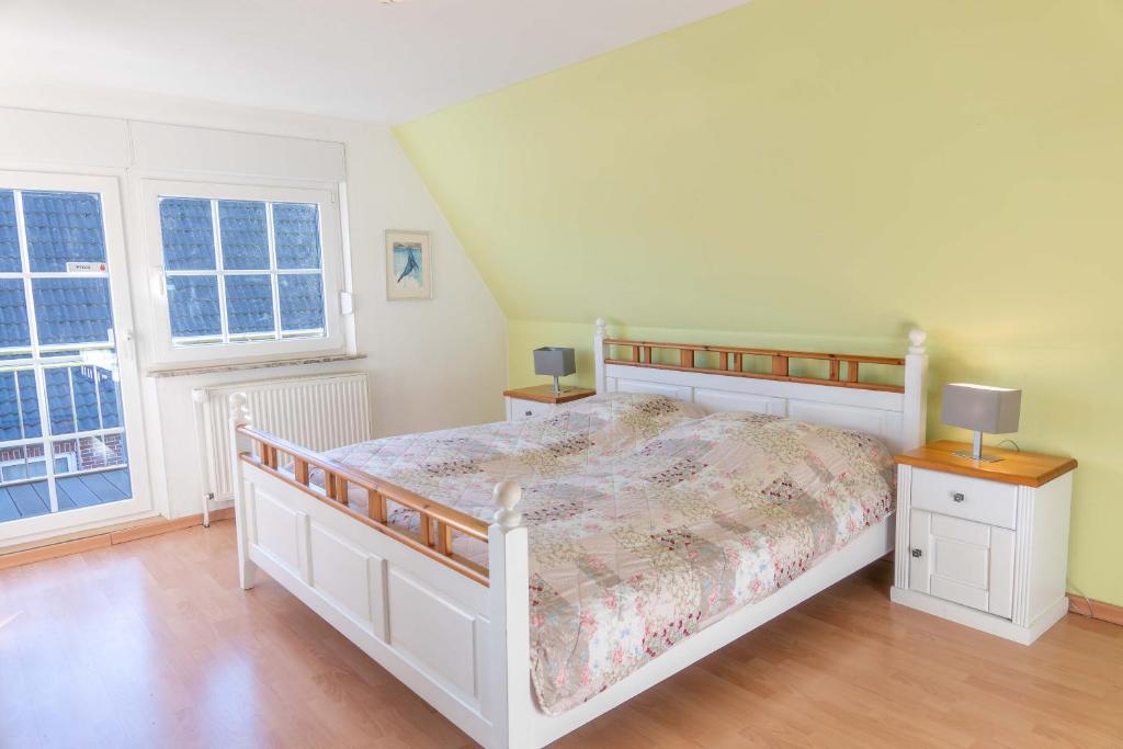 a bedroom with a white bed and two windows at Ferienhaus Nordsee2 in Dornum