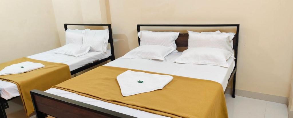 two beds in a room with white sheets and pillows at Shaktipeeth Yatrinivas in Kolhapur