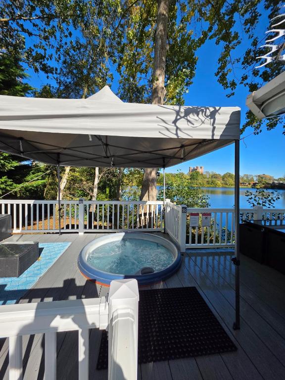 a hot tub under an umbrella on a deck at Nestled beneath the trees is this beauty a 3 bed property with hot tub and stunning views in Tattershall