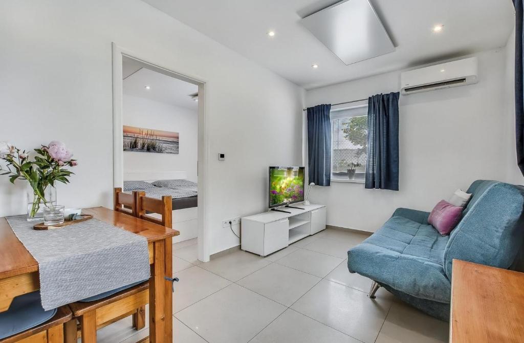 a living room with a blue couch and a tv at Apartment MINT in Senec