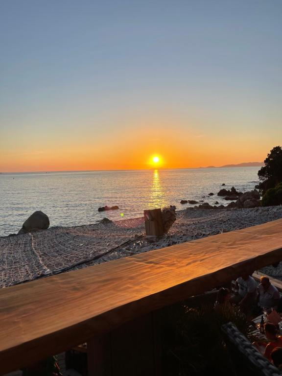 a sunset on the beach with a wooden bench at u limone in Porticcio