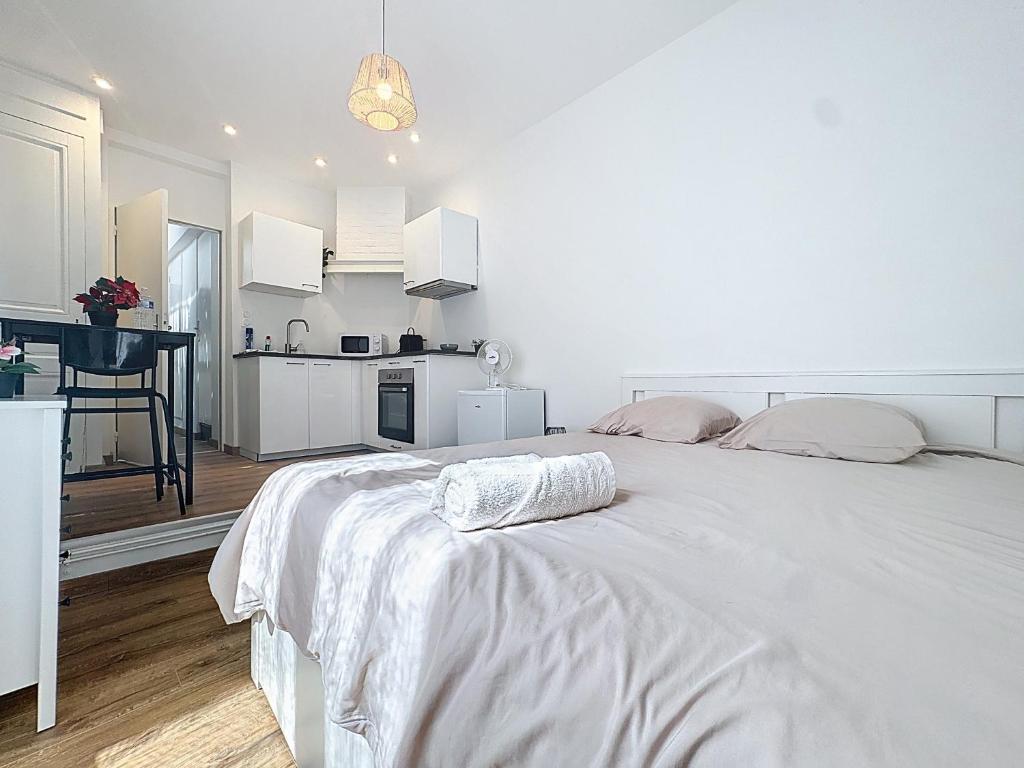 a white bedroom with a large bed and a kitchen at Appartement Cosy Saint-Chamond in Saint-Chamond