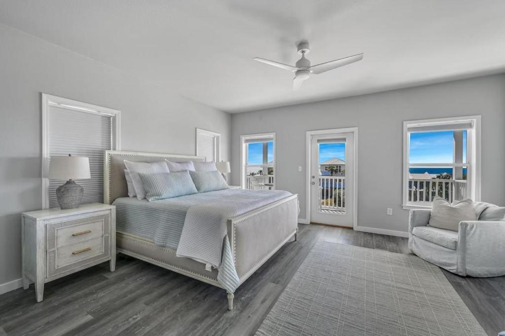 a bedroom with a bed and a chair and windows at Salty Seabreeze in Seacrest