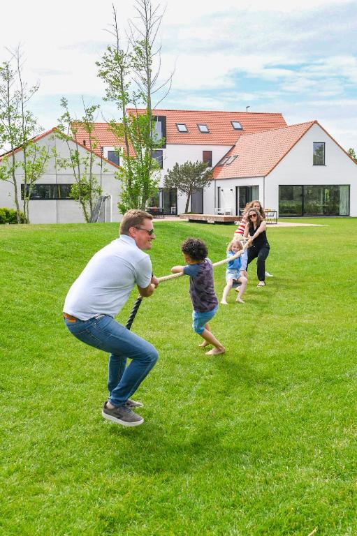 a man playing with two children in a field at DOS22 Vakantiewoning I De Haan Wenduine in Zuienkerke