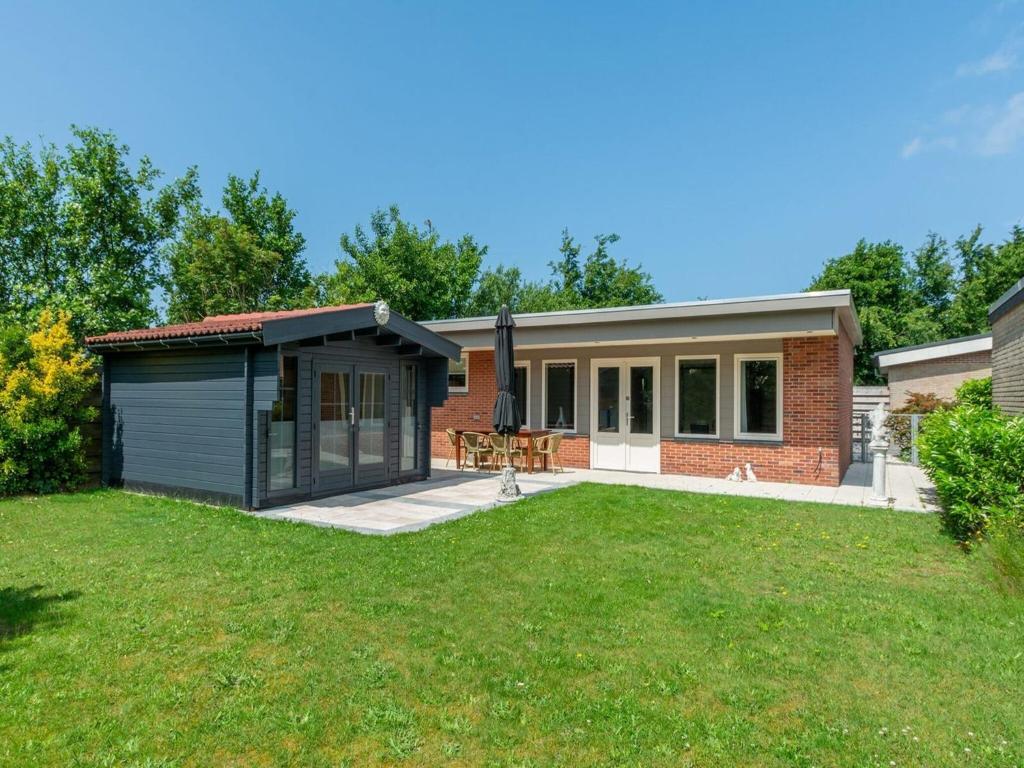 a house with a garage and a lawn at Bungalow near Dutch Coast with Private Garden in Callantsoog