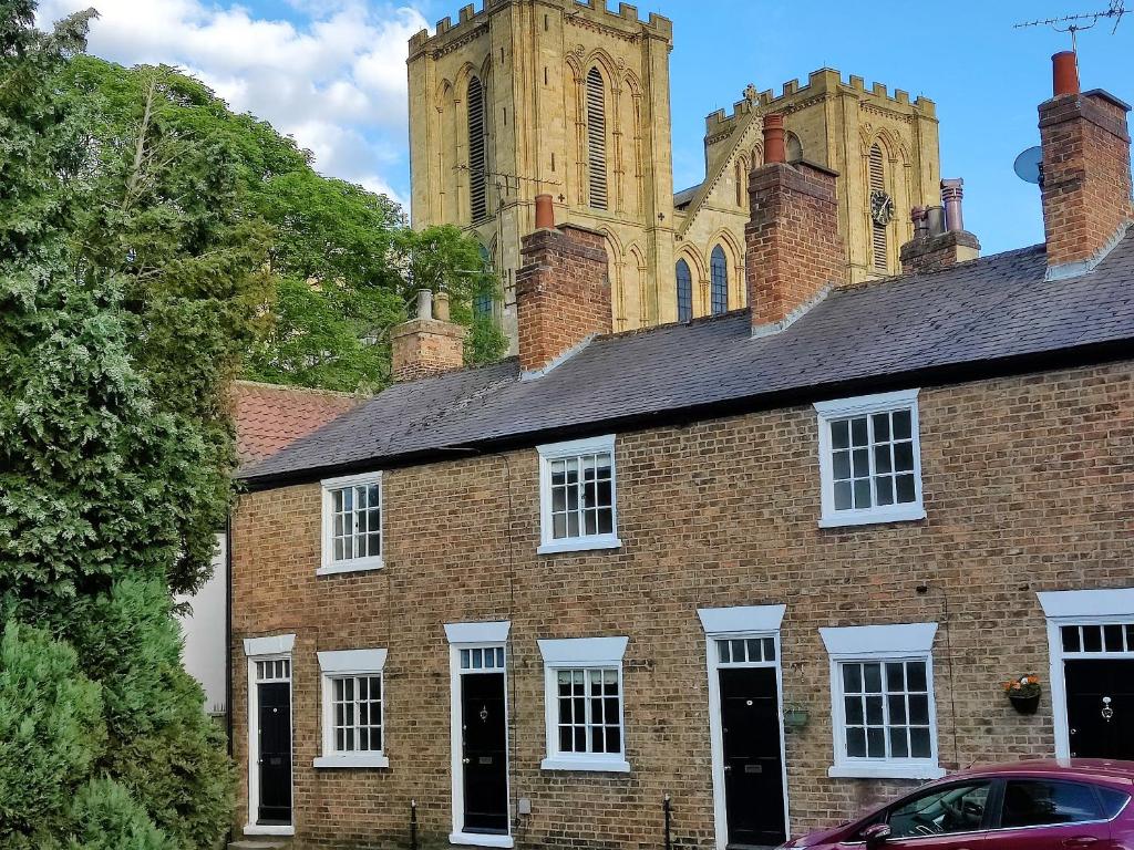 an old brick building with a church in the background at Court Terrace in Ripon