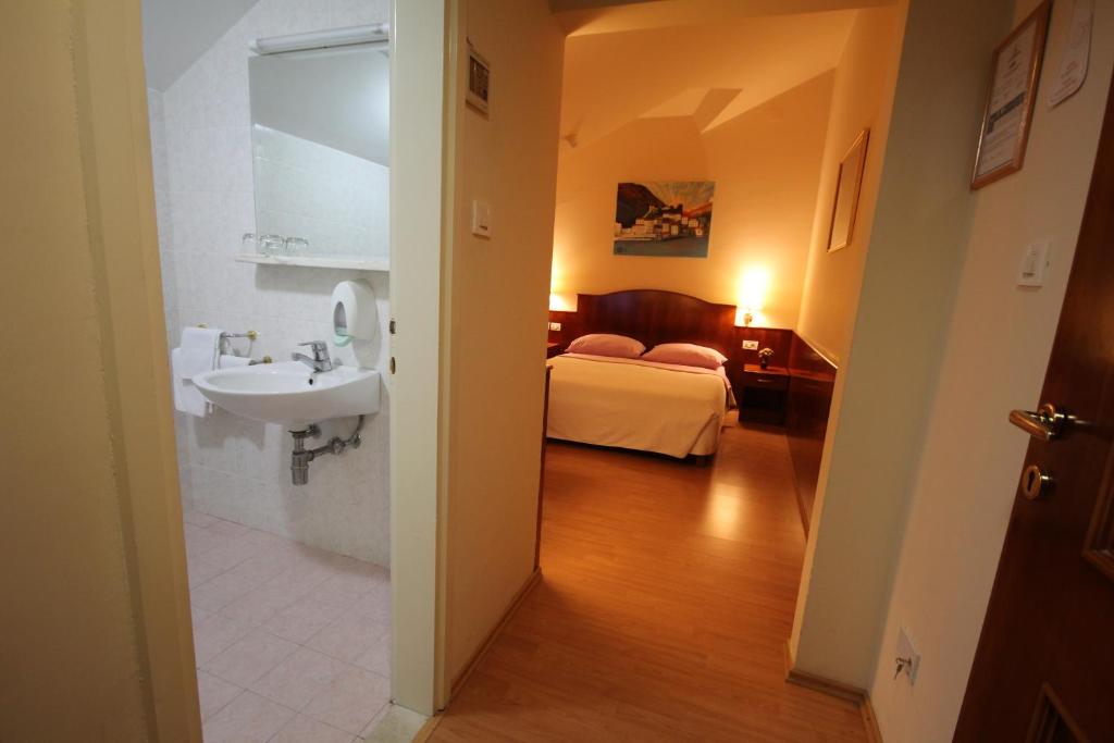 ein Badezimmer mit Waschbecken und ein Bett in einem Zimmer in der Unterkunft Villa Koruna - Mali Ston in Ston