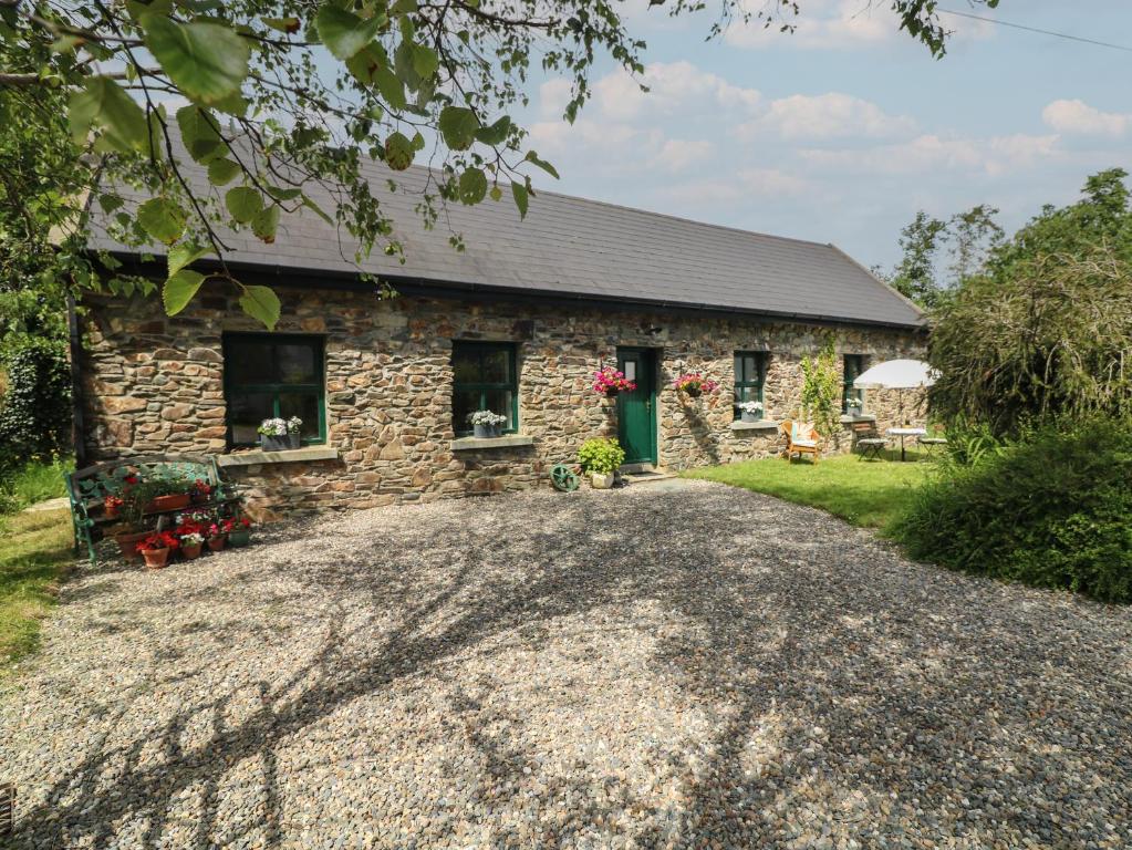 a stone house with a gravel driveway in front of it at Bohan Bo in Kilmuckridge