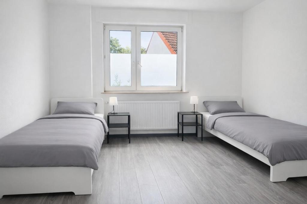 two beds in a white room with two windows at Monteur- und Ferienunterkunft Waghäusel in Waghäusel