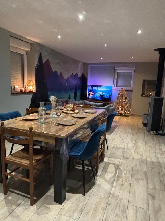 a dining room with a wooden table and a living room at Chez David & Magali in Dommartin-lès-Remiremont