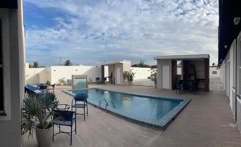 a swimming pool with chairs and tables on a patio at Divine Duplex Próximo ao Oficina 23 Kite Surf in Caucaia
