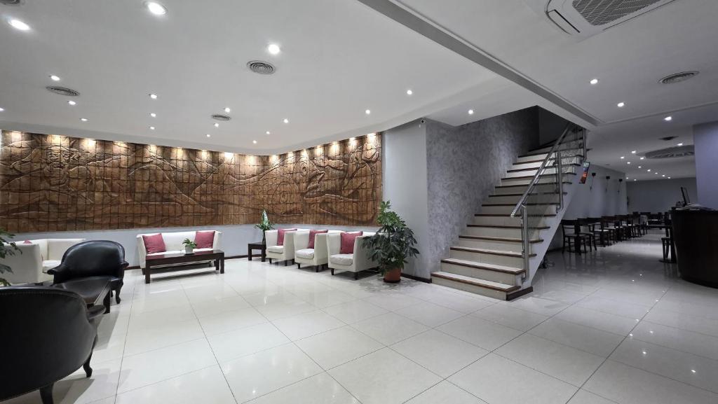 a lobby with a staircase and tables and chairs at Hotel Neptuno in Mar del Plata