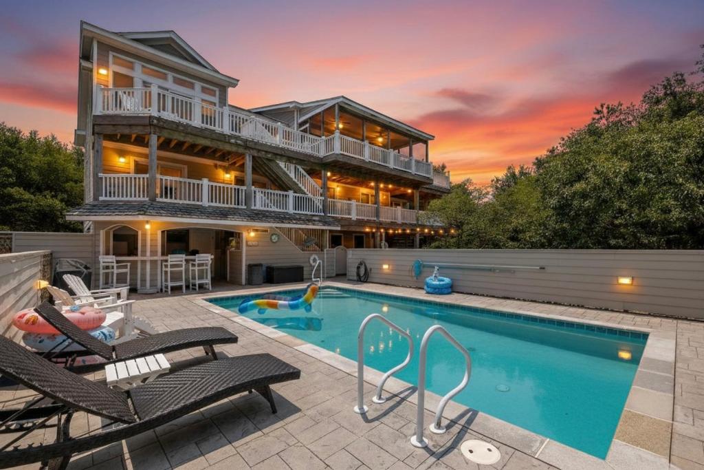 a home with a swimming pool and a house at Beach Cabana - Southern Shores, 6 En-Suites, Elevator, Pool, Cabana Bar, Hot Tub, Game Room in Southern Shores
